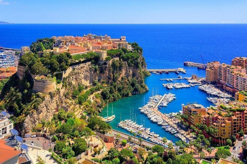 A coastal town with a marina, buildings, and a cliff. 1