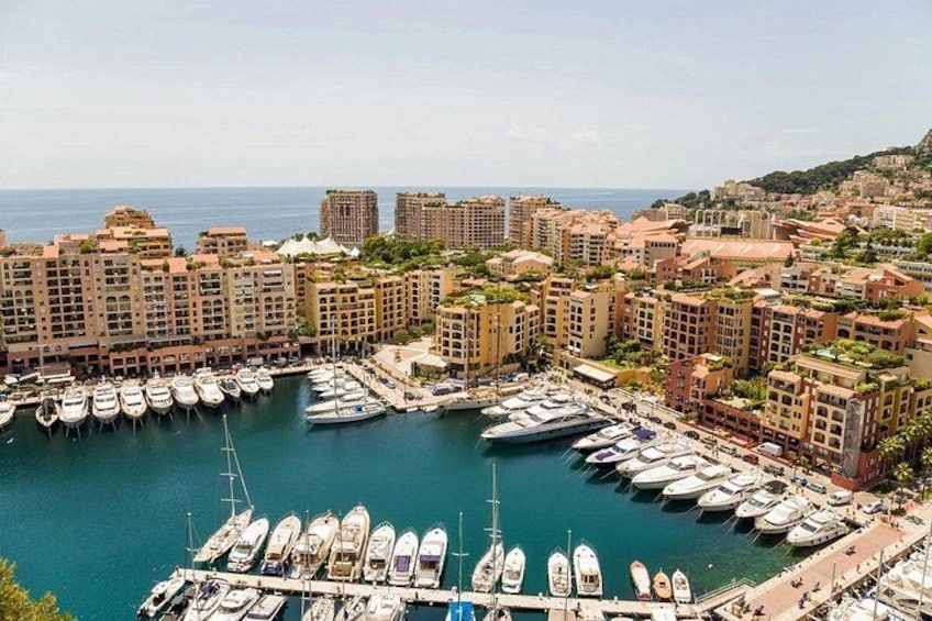A marina with numerous boats docked, surrounded by residential buildings and a hilly landscape in the background. 5