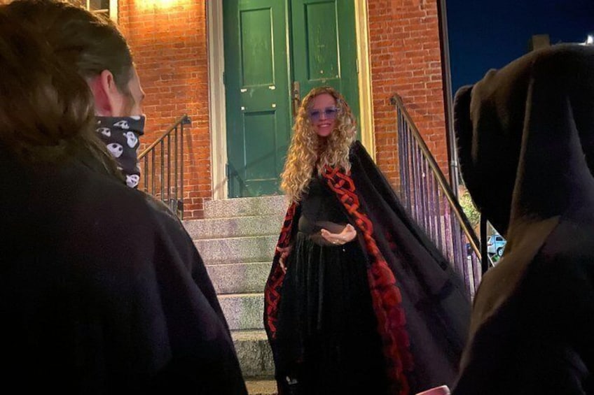 A person in a black dress with a red and black cape standing on a brick staircase. 2