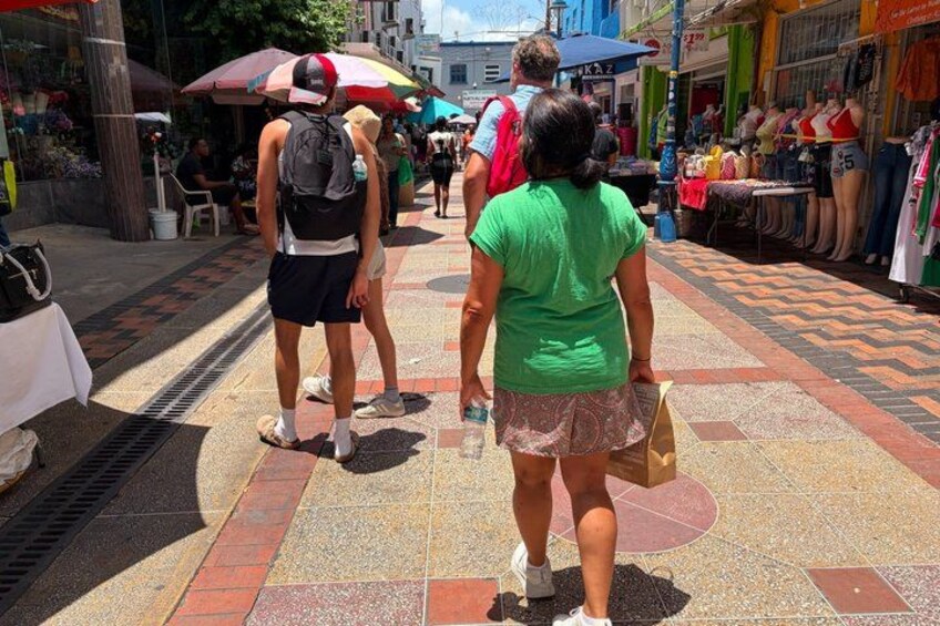 Una calle peatonal con tiendas y gente caminando. 3