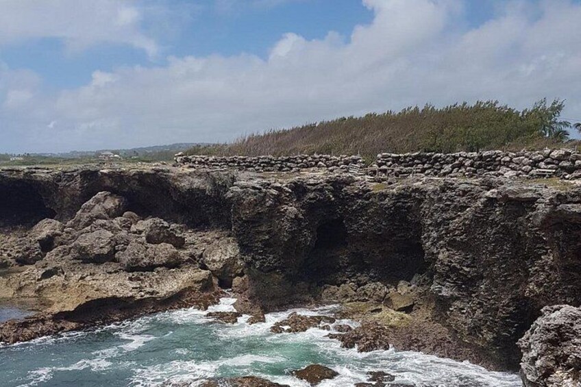A coastal cliff with a rocky shoreline and waves crashing against it. 5