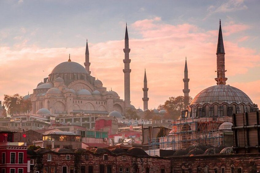 Une mosquée dotée de plusieurs coupoles et de plusieurs minarets, entourée de bâtiments urbains. 1
