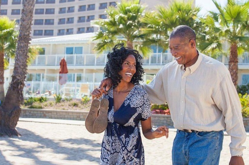 A couple walking on a beach with palm trees and a hotel in the background. 3