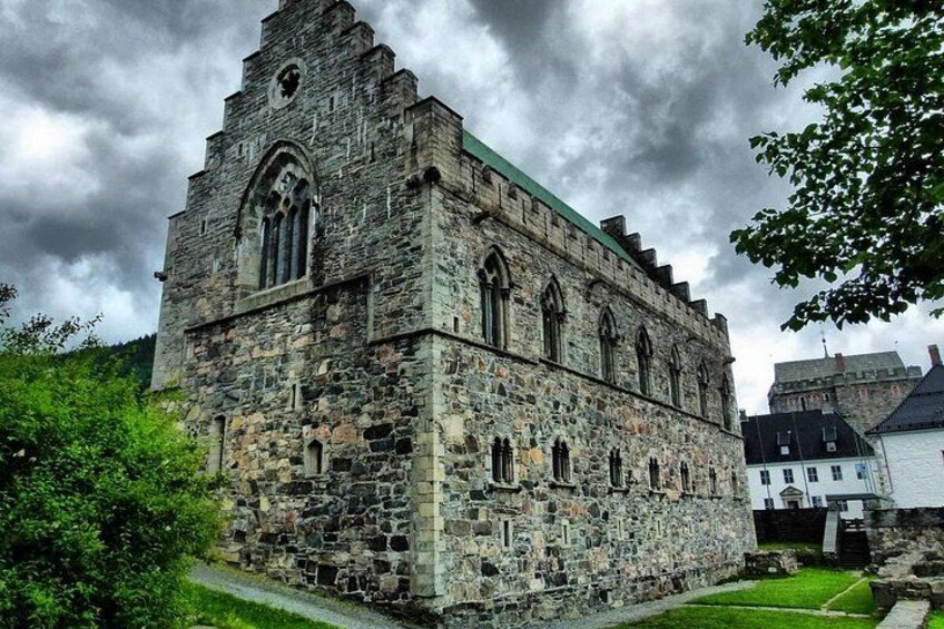 A historic stone building with arched windows and a steep roof. 5