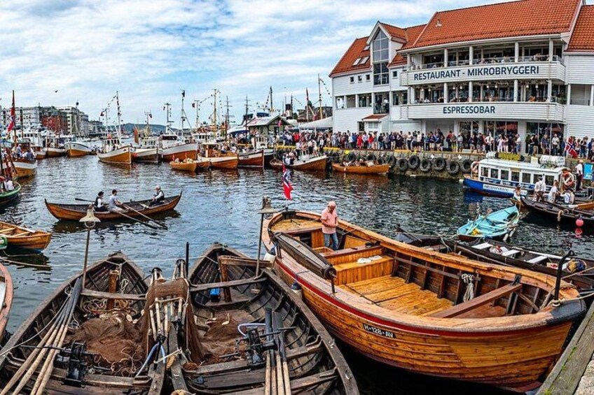 A harbor with wooden boats docked, a restaurant named 'Mikrobryggeri' with an 'ESPRESSO BAR' sign, and a crowd of people on the pier. 4