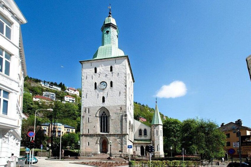 A historic church with a clock tower and a green dome. 1