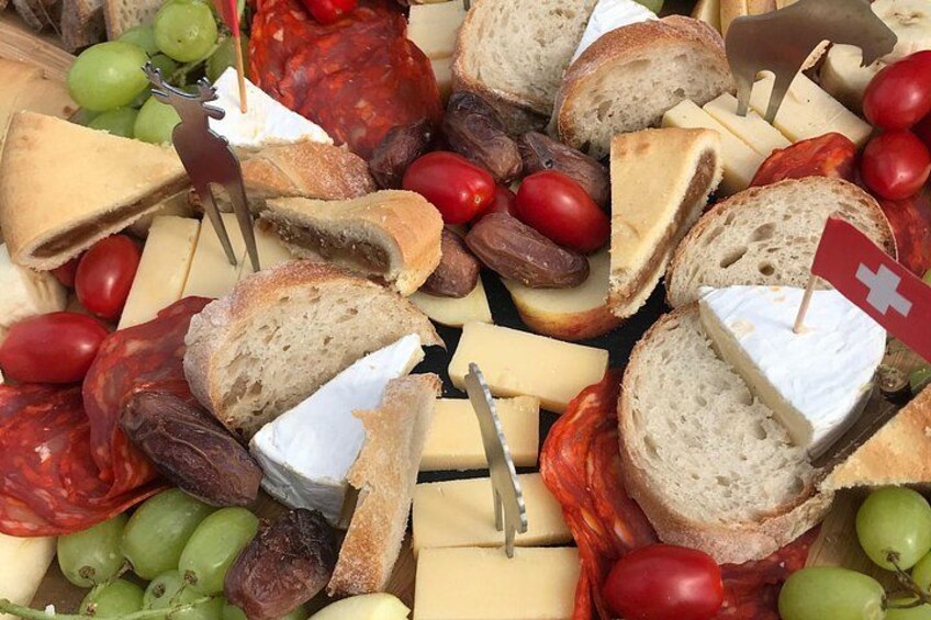 Una tabla de quesos con diferentes tipos de queso, pan, uvas y tomates. 3