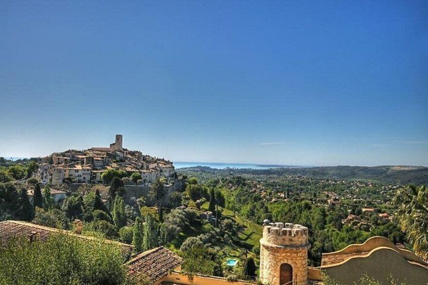 A historic town with a prominent church on a hill, surrounded by lush greenery and a clear blue sky. 4
