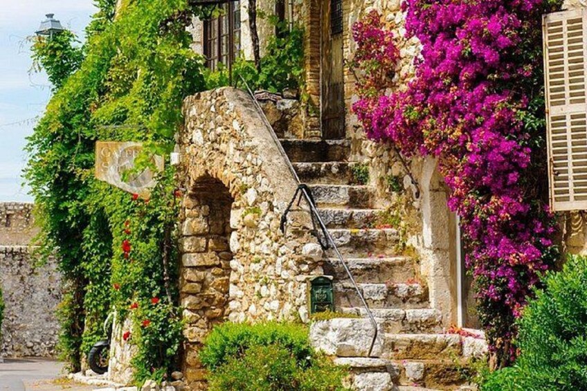 Un escalier en pierre avec une rampe en bois, entouré d’une végétation luxuriante et de magnifiques fleurs de bougainvillier. 3