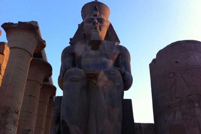 A large seated statue with a headdress and a figure holding a staff. 5