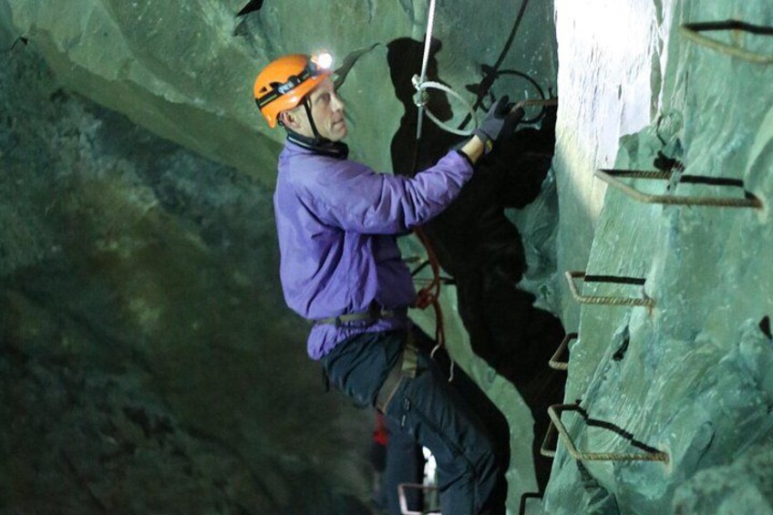 A person climbing a rock wall with safety harnesses and ropes. 4