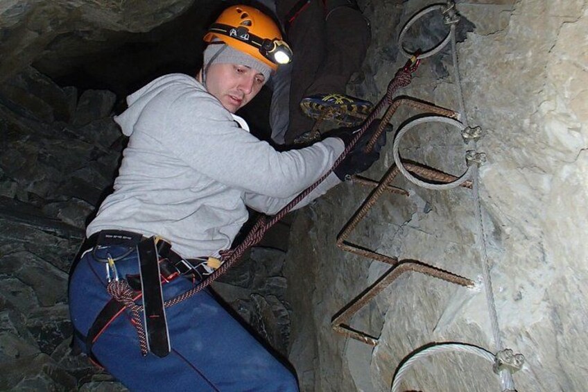 A person climbing a metal ladder in a rocky environment. 3