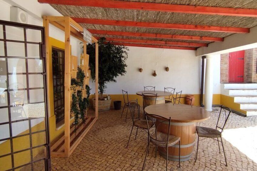 Un patio al aire libre con una mesa redonda de madera, sillas, una planta en maceta y una puerta roja. 4