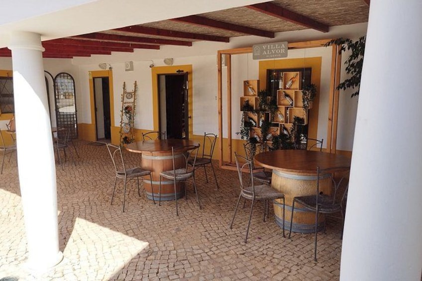 Un espacio de comedor al aire libre cubierto, con mobiliario rústico, una mesa de madera y una decoración con plantas. 4