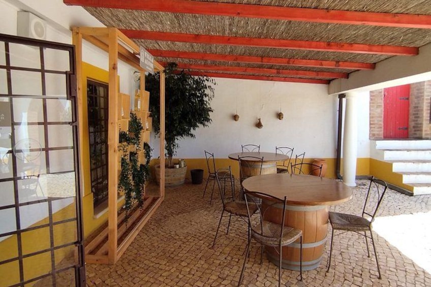 Un patio al aire libre con una mesa redonda de madera y sillas, una planta en maceta y una puerta roja. 3
