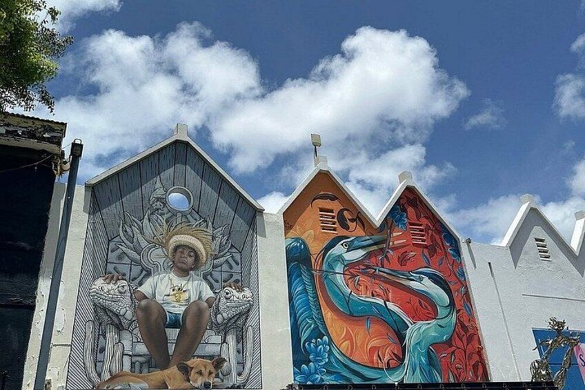 Un mural con una figura sentada y un ave en un edificio. 5