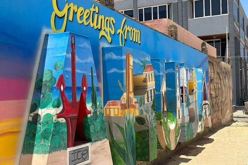 Un mural colorido con el texto 'Greetings from' y diversos edificios y monumentos. 4