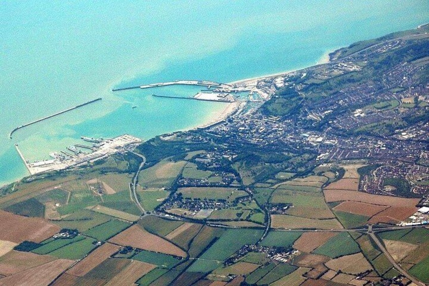 An aerial view of a coastal town with a harbor, farmland, and a large body of water. 3