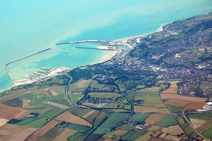 An aerial view of a coastal town with a marina, farmland, and a beach. 4