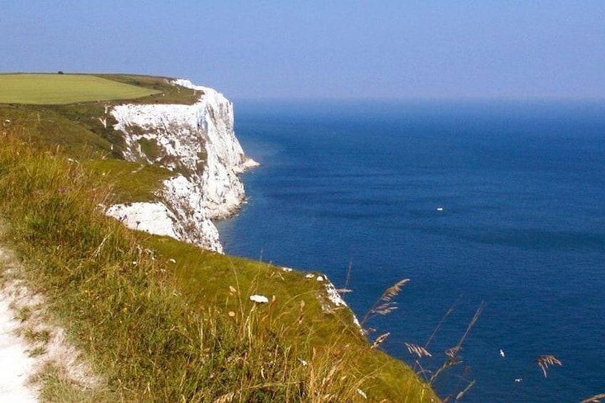 A coastal cliff with a grassy path leading to the edge. 3