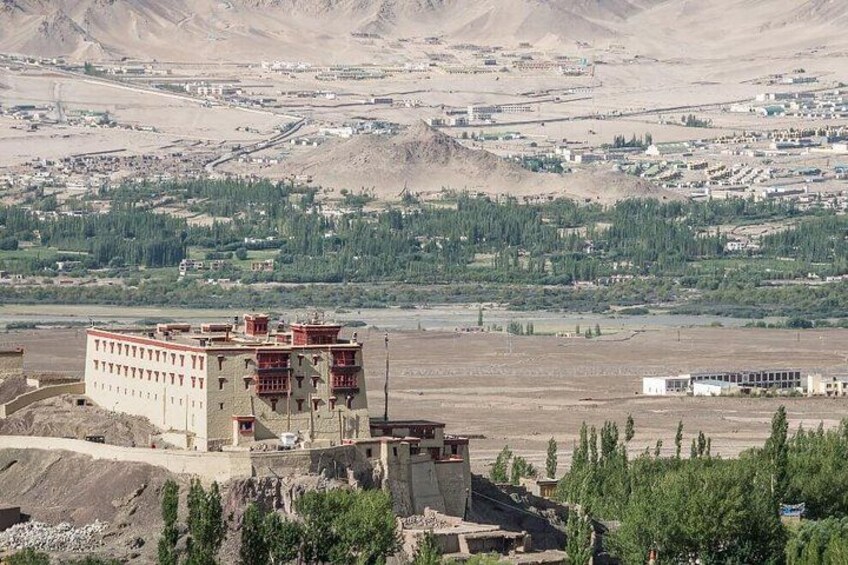 A mountainous landscape with a large building in the foreground and a town in the background. 5