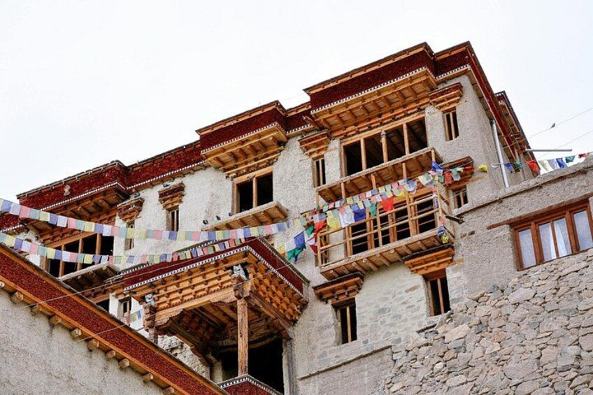 A traditional multi-story building with wooden balconies and colorful prayer flags. 3