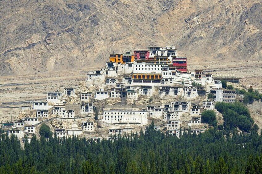 A monastery complex with multiple buildings, surrounded by a forest and mountains. 4