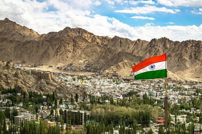 A mountainous landscape with a flag, buildings, and greenery. 4