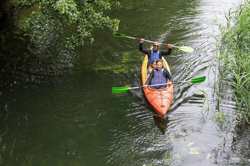 A person kayaking on a river surrounded by greenery. 5