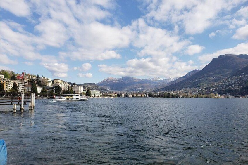 Ein See mit einem Boot, Häuser am Ufer und Berge im Hintergrund. 4