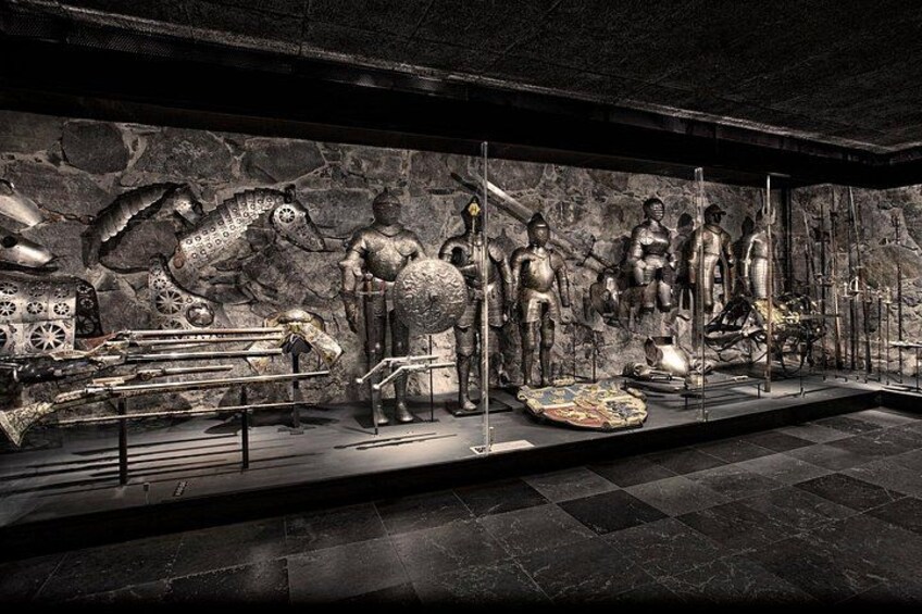 Una mostra museale con armature antiche, scudi e una statua equestre. 3