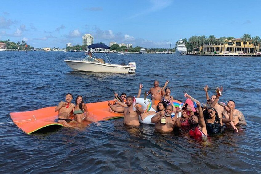 Een groep mensen op een boot in het water, met gebouwen op de achtergrond. 3