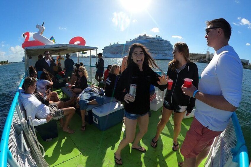 A group of people on a boat with a large cruise ship in the background. 1