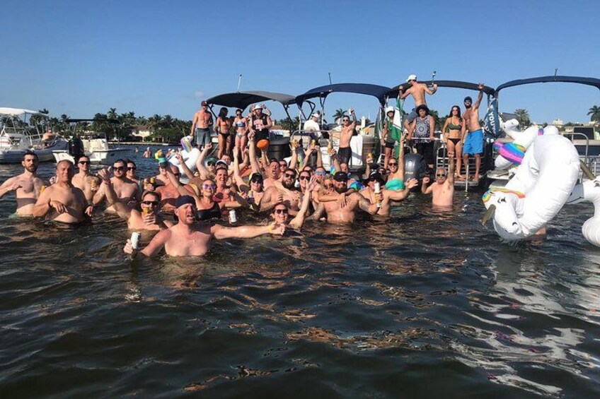 A group of people on a boat in a body of water, some standing and some sitting, with a large inflatable swan decoration. 5