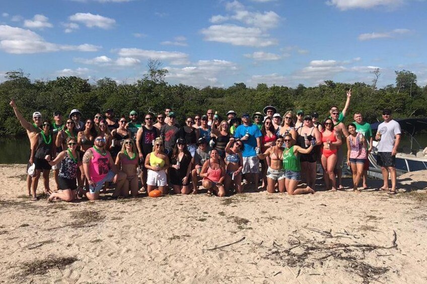 A group of people on a sandy beach with trees in the background. 2