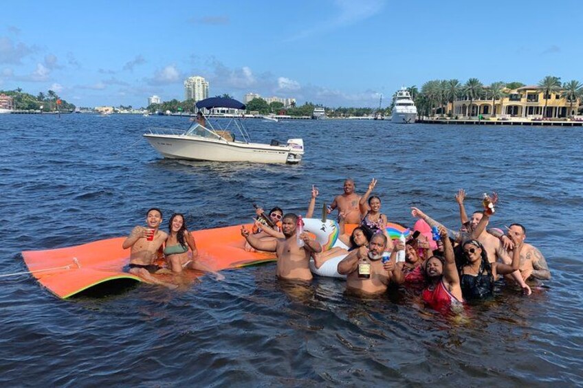 A group of people on a boat in a body of water with a cityscape in the background. 3