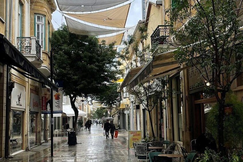 A wet street with shops, trees, and outdoor seating. 2