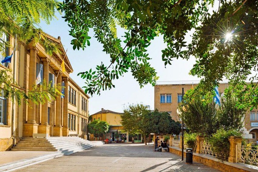 A street with a building on the left, a bench on the right, and trees in the foreground. 2