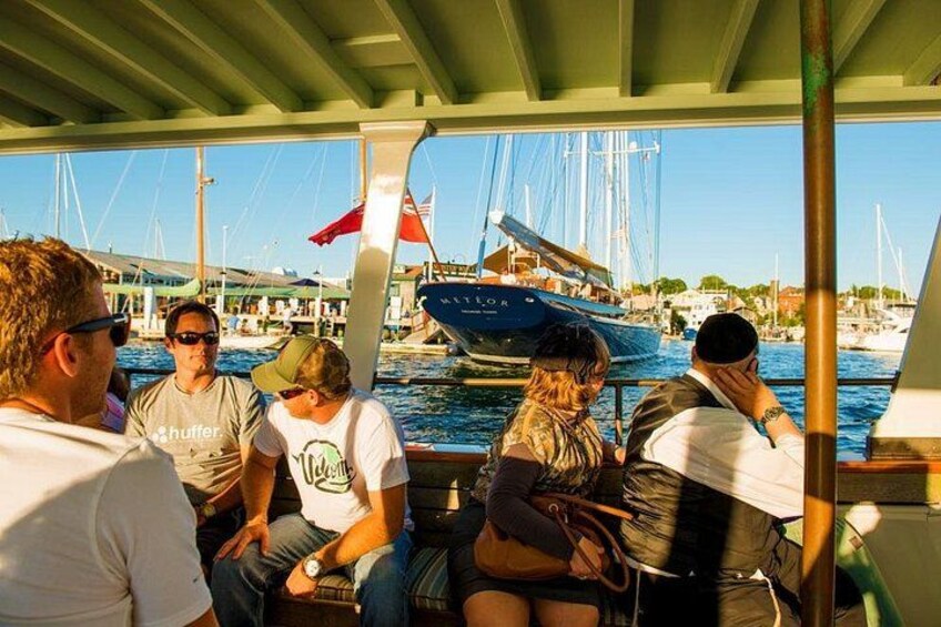 Un groupe de personnes se trouve sur un bateau, avec un port de plaisance et des voiliers en arrière-plan. 3