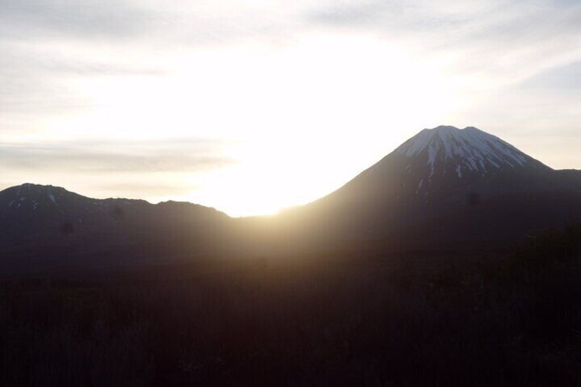 A mountain with a snow-capped peak and the sun setting behind it. 5