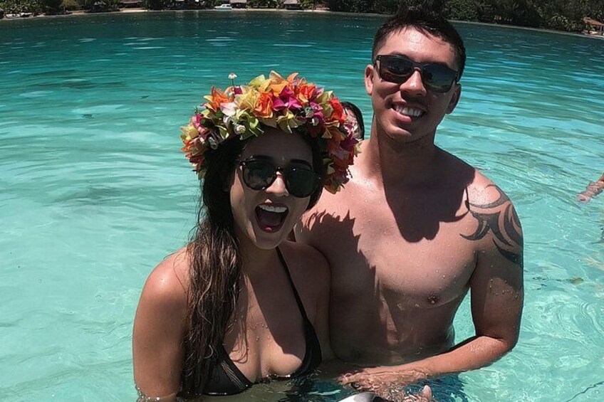 Two people in a clear blue pool with one wearing a floral headpiece. 2