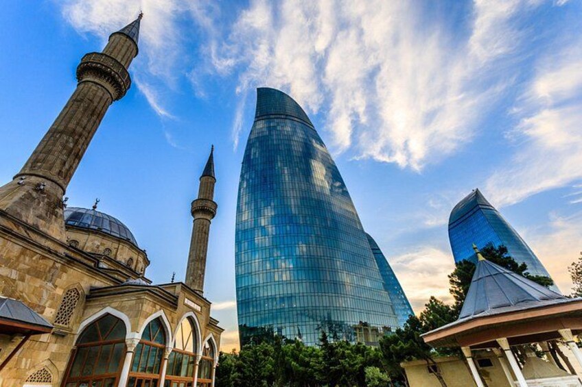 A mosque with two minarets and a modern glass building. 1
