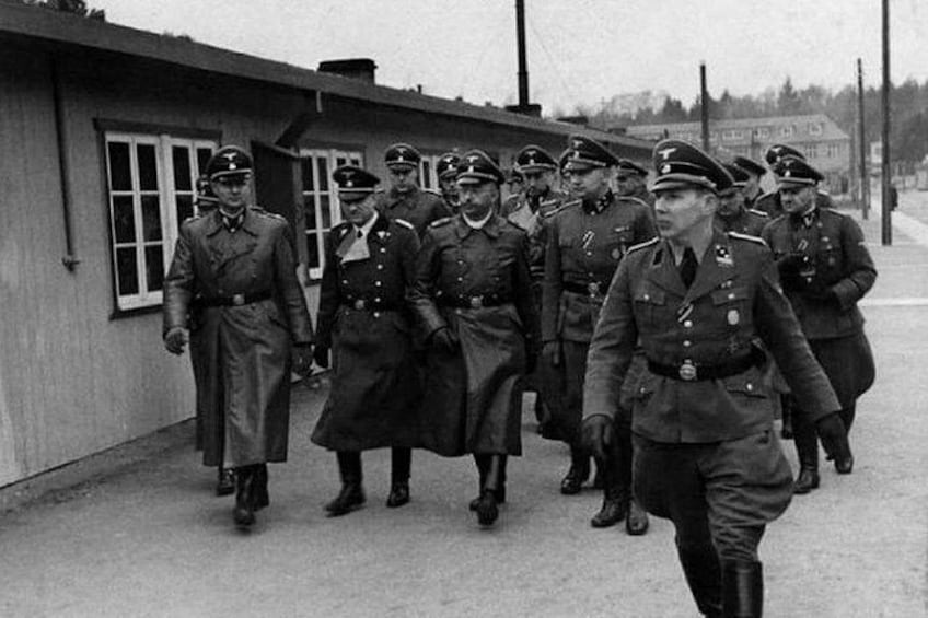 Un grupo de personas con uniforme caminando en fila por una calle. 3