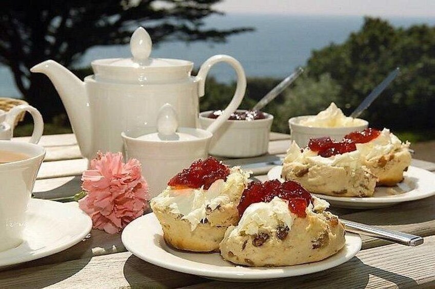 A table with tea set, scones with jam, and a view of the sea. 2