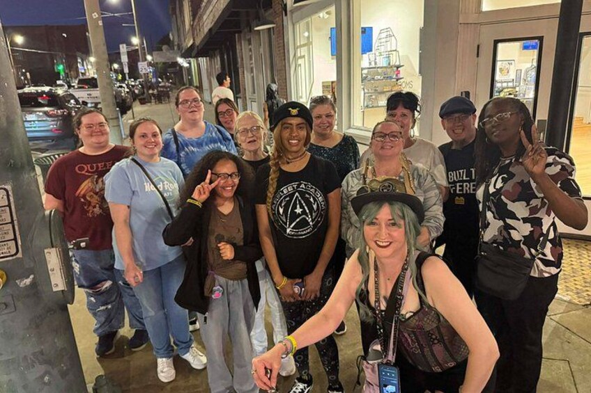 A group of people posing for a photo on a city street at night. 3