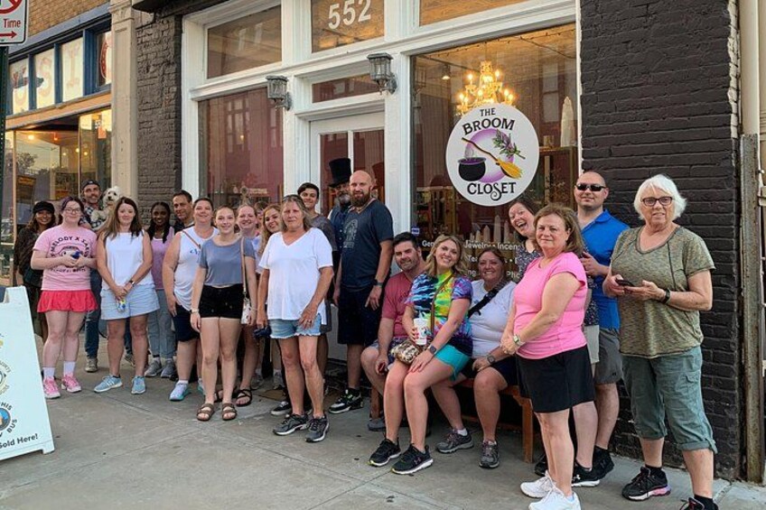 A group of people standing in front of a storefront with a sign that reads 'The Broom Closet.' 3