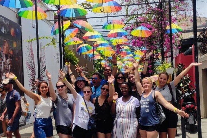 A group of people posing under colorful umbrellas in an outdoor setting. 2