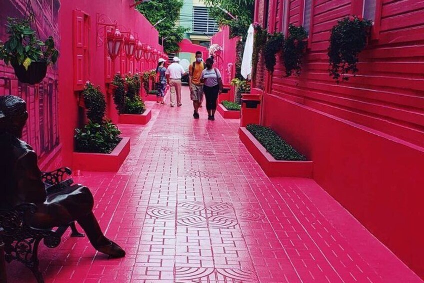 A red-walled alley with patterned flooring, benches, and potted plants. 1