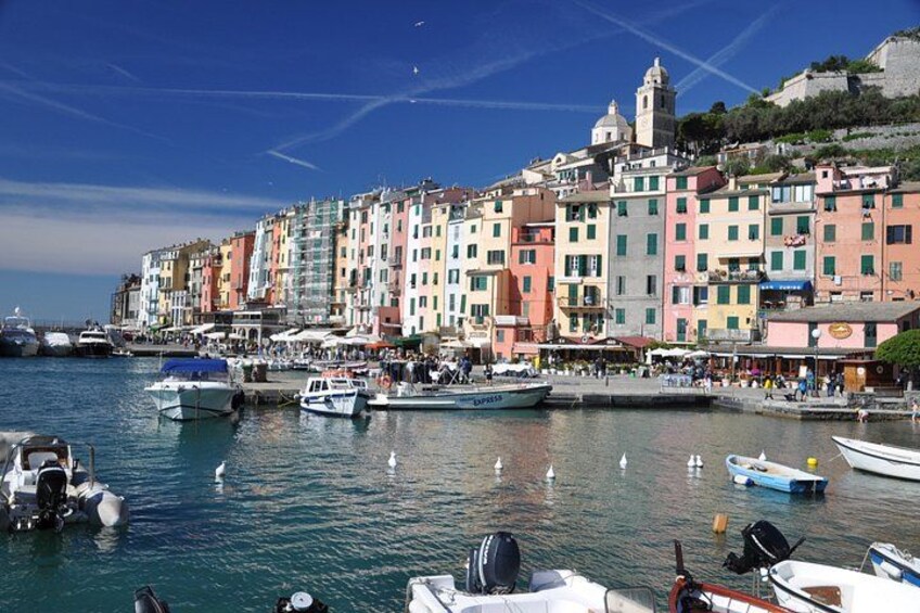 Una località costiera con edifici colorati, un porto turistico con barche e un cielo azzurro limpido. 2