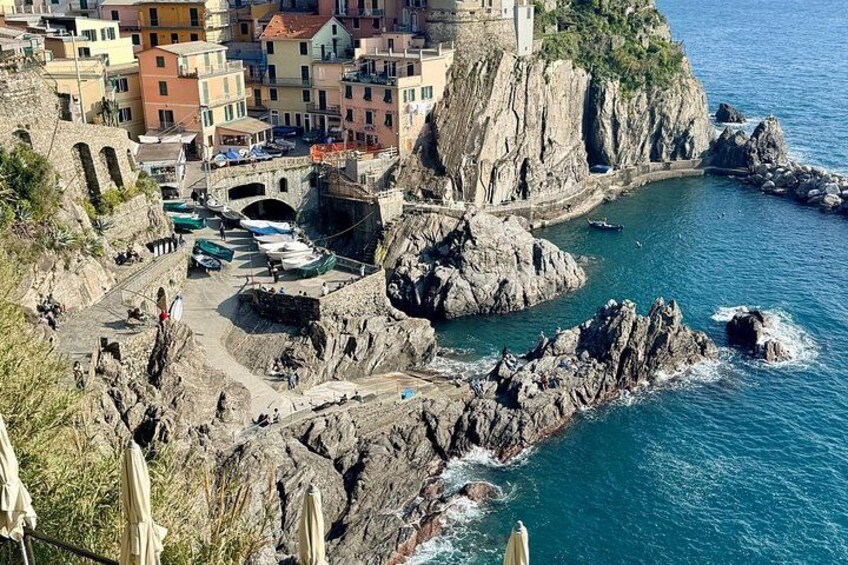 Una località costiera con edifici colorati, scogliere rocciose e barche ormeggiate lungo la riva. 4